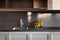 Clean and empty kitchen with wooden cabinets and dark worktop. Steel sink and two transparent yellow, amber vases