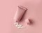 Clean facial body cream tube of pink color with open cap and product squeezed cream texture on flesh color background