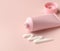 Clean facial body cream tube of pink color with open cap and product squeezed cream texture on flesh color background