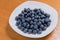 Clean freshly picked blueberries on white plate - close up studio shot.  Ingredients:  Antioxidants , Vitamin C, Antioxidant