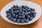 Clean freshly picked blueberries on white plate - close up studio shot.  Ingredients:  Antioxidants , Vitamin C, Antioxidant