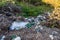 Clean little creek polluted with human trash, conceptual image of human negligence.