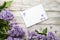 Clean notepad with spring lilac flowers on white wooden background in very peri trendy color of the year 2022