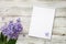 Clean notepad with spring lilac flowers on white wooden background in very peri trendy color of the year 2022