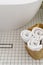 Clean rolled towels in wicker basket on bathroom floor