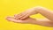 Clean well manicured hands of a young woman, skin care on light yellow background. massaging against white background