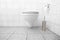 Clean white bathroom with toilet paper and toilet brush with withe tiles and a floating toilet