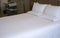 Clean white bed in hotel. White comfortable pillow on bed in bedroom. Bed sheets and pillows.