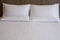 Clean white bed in hotel. White comfortable pillow on bed in bedroom. Bed sheets and pillows.