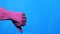 Cleaner hand in purple rubber glove on blue background. Like and dislike gesture.