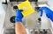 Cleaner sprinkles detergent on a cloth for cleaning the kitchen. Man cleaning a gas stove. closeup. Cleaning of gas cooker