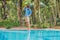 Cleaner of the swimming pool . Man in a blue shirt with cleaning