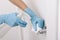 Cleaning black door handle with an antiseptic wet wipe, blue gloves and sanitizer. Sanitize surfaces prevention in