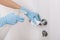 Cleaning black door handle with an antiseptic wet wipe, blue gloves and sanitizer. Sanitize surfaces prevention in