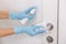 Cleaning black door handle with an antiseptic wet wipe, blue gloves and sanitizer. Sanitize surfaces prevention in