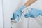 Cleaning black door handle with an antiseptic wet wipe, blue gloves and sanitizer. Sanitize surfaces prevention in