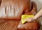 Cleaning brown sofa with a yellow cloth