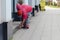 Cleaning of a city street - the worker the yard keeper in a uniform collects garbage by hands near a building.