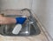 Cleaning. A cleaning lady in blue rubber gloves washes a sink with a spray bottle