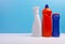 Cleaning concept with various plastic bottles and canisters on blue background. Various detergents and the necessary attributes