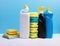 Cleaning concept with various plastic bottles canisters and sponges on blue background. Various detergents and the necessary