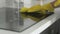 Cleaning cooktop cooking panel in kitchen with fat remover spray and yellow rag by a woman in yellow rubber gloves.