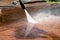 Cleaning dirty backyard paving tiles with pressure washer cleaner