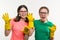 Cleaning, domestic duties and teamwork concept. Two teenage sisters wearing yellow protective gloves