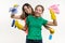 Cleaning, domestic duties and teamwork concept. Two teenage sisters wearing yellow protective gloves and holding them for cleaning