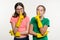 Cleaning, domestic duties and teamwork concept. Two teenage sisters wearing yellow protective gloves show sign quieter, secret
