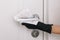 Cleaning door handle with dirty wipe in black gloves. Sanitize surfaces prevention in hospital and public spaces against