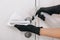 Cleaning door handle with dirty wipe in black gloves and sanitizer spray. Disinfection in hospital and public spaces