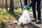 Cleaning garbage in bags in the park. Close-up of a volunteer collecting plastic waste. World cleaning or Earth day, Generative AI