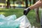 Cleaning garbage in bags in the park. Close-up of a volunteer collecting plastic waste. World cleaning or Earth day, Generative AI