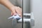 Cleaning glass door handles with an antiseptic wet wipe. Woman hand using towel for cleaning home room door link