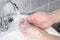 Cleaning hands from dirt, bacteria and viruses with tap water in the bathroom to protect against flu and illness