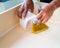 Cleaning and home concept - close up of male brooming wooden floor with small whisk broom and recycled milk boxes as dustpan