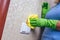 Cleaning in the house. A girl in green gloves wipes the electricity switch with a yellow cloth. cleaning from dust. Blue