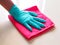 Cleaning in house with hand wearing rubber gloves and wiping dust with red cloth