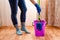 Cleaning the house with a lilac bucket, blue gloves, a mop and cleaning lady`s feet. Home cleaning concept