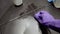 Cleaning lady clean tiled floor with detergents and washcloths. Hands in purple gloves