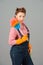Cleaning lady with colored duster and orange latex gloves in pin-up style. Brunette curl retro styled housekeeper on grey studio