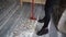 Cleaning lady in high heels cleans the house after a party. Sweep the floor with confetti with a broom. Close-up of