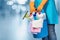 A cleaning lady is holding a bucket of cleaning products on a blurred background