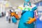 A cleaning lady in a mask holds a spray and a bucket of cleaning products in her hand