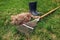 Cleaning lawn from dry grass with a rake in spring garden. Heap of grass with boots and tool