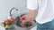 Cleaning organic cucumbers and tomatoes in the kitchen. A woman washes fresh green cucumbers and tomatoes with her hands