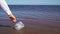 Cleaning the sea coast from plastic. Close-up of a man collecting plastic garbage on a sandy beach in summer.