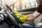 Cleaning service. Man in uniform and yellow gloves washes a car interior in a car wash