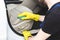 Cleaning service. Man in uniform and yellow gloves washes a car interior in a car wash. Worker washes the chairs of the